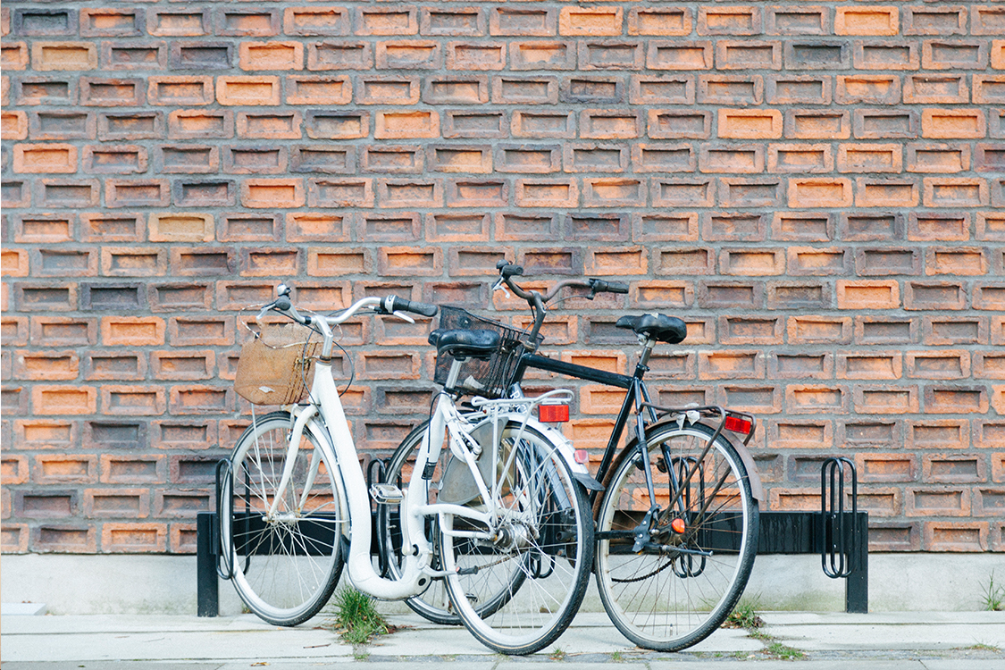 Parking para bicicletas pegado a pared de ladrillos con dos bicicletas