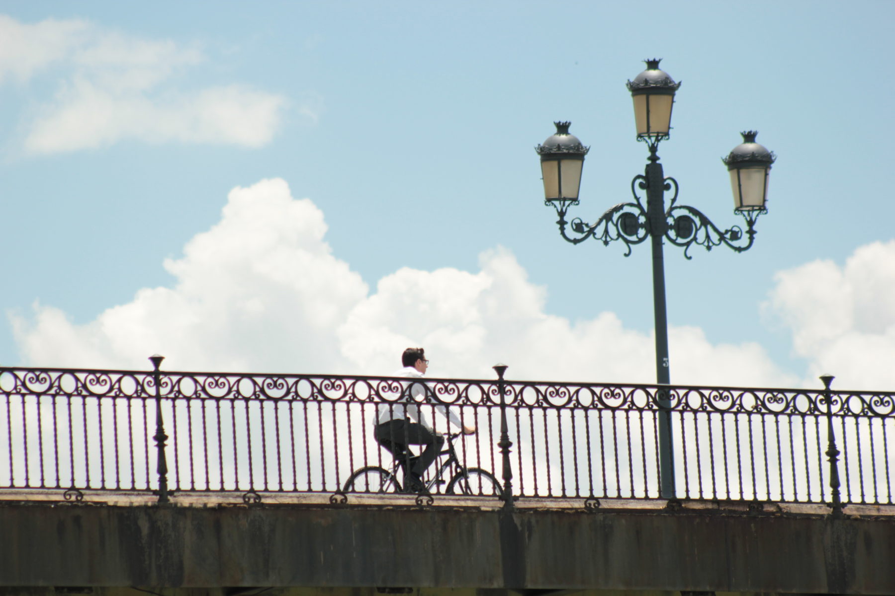 Un ciclista paseando por el Puente de Triana en Sevilla