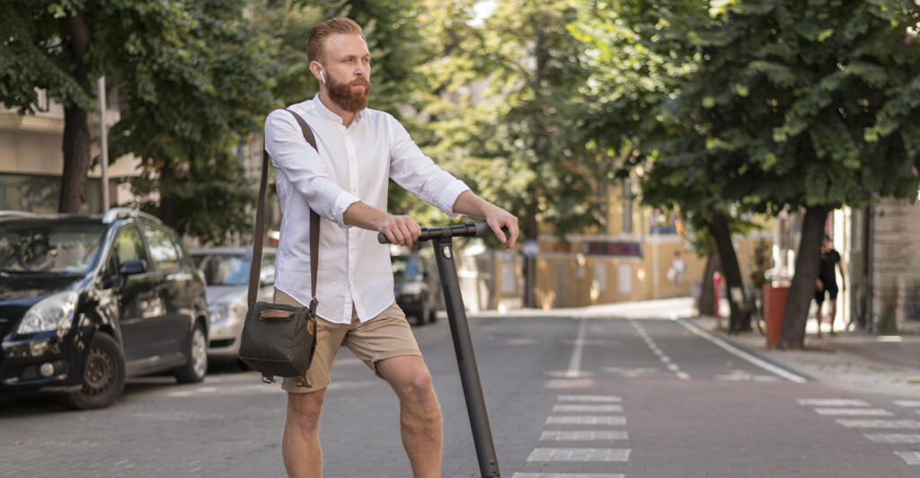 Chico con barba en patinete cumpliendo con la ley de movilidad sostenible