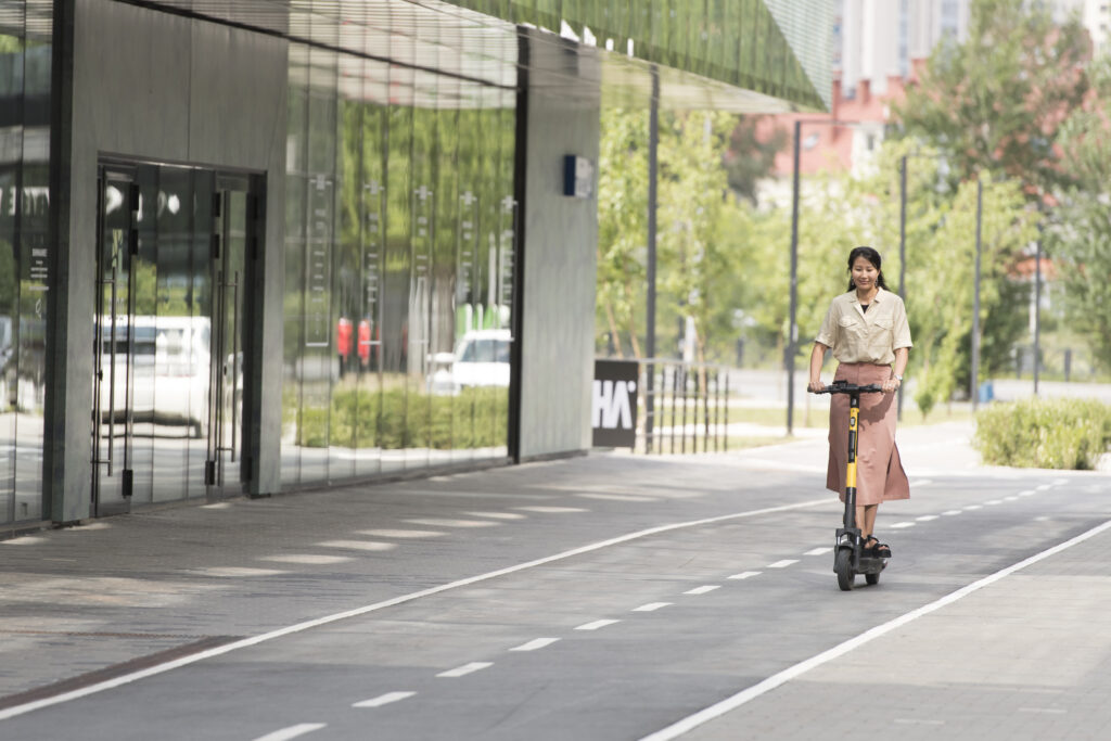 Mujer que participa en el Urban Mobility Challenge va en patinete al trabajo